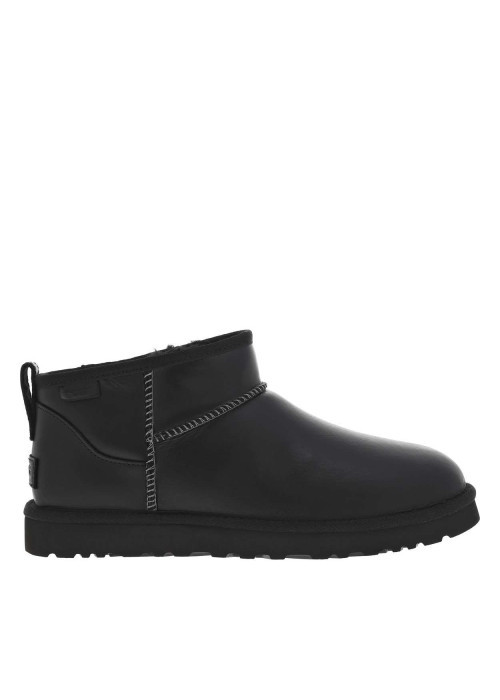 Boots en cuir noires à talon plat avec des surpiqûres noires et blanches